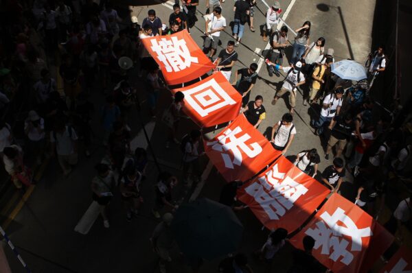 Протестующие несут баннеры с надписью «прекратите промывать нам мозги» во время акции протеста против усилий правительства по внедрению национального образования в Гонконге 29 июля 2012 г. Dale de la Rey / AFP / GettyImages