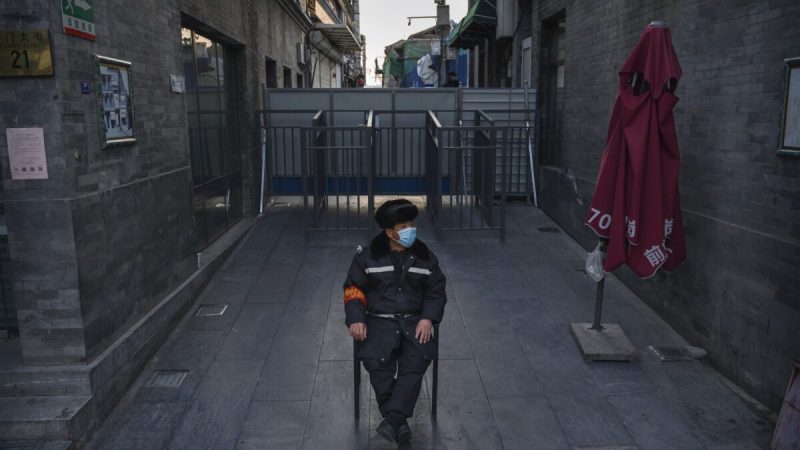 Китайский охранник в защитной маске наблюдает за зоной возле баррикады, отделяющей жилой квартал от коммерческого района в Пекине, Китай, 11 марта 2020 г. (Kevin Frayer/Getty Images)  | Epoch Times Россия