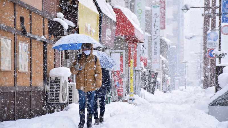 Люди идут по улице в городе Тояма в сильный снегопад, принесённый экстремальным холодным фронтом в западные и северные районы страны 27 декабря 2021 года. (JIJI Press/AFP via Getty Images)
 | Epoch Times Россия