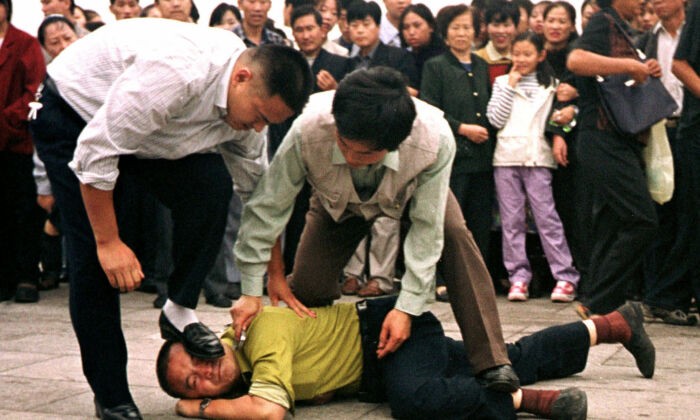 Два полицейских в штатском арестовывают практикующего Фалуньгун на площади Тяньаньмэнь в Пекине 31 декабря 2000 г. (Chien-min Chung/AP Photo) | Epoch Times Россия