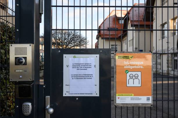 плакат у входа в кампус Шатеньере Международной школы Женевы, закрытый после того, как были обнаружены два ящика варианта Омикрон, в Фунексе, Швейцария. Фото: FABRICE COFFRINI/AFP via Getty Images) | Epoch Times Россия