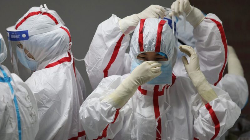 Медицинский персонал надевает защитное снаряжение перед осмотром пациентов с коронавирусом COVID-19 в больнице Красного Креста в Ухане, Китай, 16 марта 2020 года. Фото: STR/AFP via Getty Images
 | Epoch Times Россия