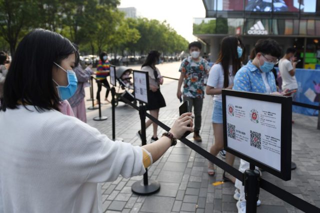 Женщина сканирует QR-код с помощью приложения для отслеживания коронавируса перед входом в торговый центр в Пекине, 2 мая 2020 года. Здесь проверяется состояние её здоровья и статус поездки. (Фото: Greg Baker/AFP über Getty Images)