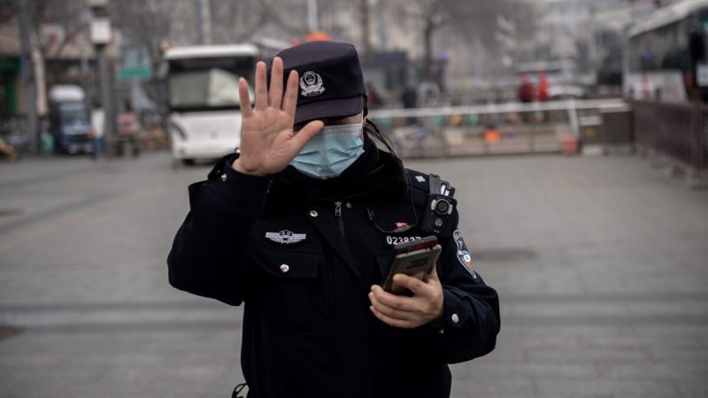 Полицейский жестом просит журналиста не фотографировать в Пекине, Китай, 5 марта 2021 года. (NICOLAS ASFOURI/AFP via Getty Images)  | Epoch Times Россия