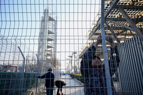 Рабочие с помощью стяжек фиксируют забор, чтобы создать «пузырь» вокруг Олимпийского парка в Пекине 4 января 2022 года. Фото: NOEL CELIS/AFP via Getty Images