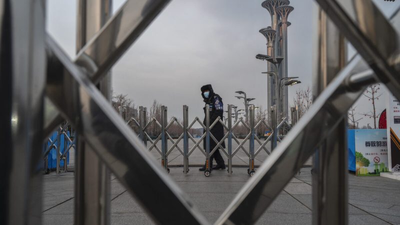 Охранник за шлагбаумом возле Национального стадиона, известного как «Птичье гнездо», который станет частью «пузыря», закрытого для посетителей и местных жителей, на зимних Олимпийских и Паралимпийских играх 2022 года в Пекине. Башня в Олимпийском парке в Пекине, Китай, 19 января 2022 года. (Kevin Frayer/Getty Images)  | Epoch Times Россия