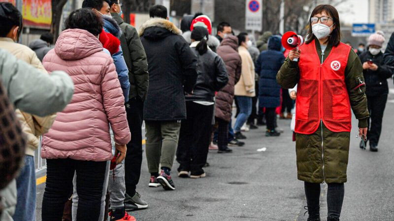 Женщина использует громкоговоритель, чтобы дать совет жителям, когда они выстраиваются в очередь во время массового тестирования в Тяньцзине, Китай, 9 января 2022 года. (Sun Fanyue/Xinhua via AP) | Epoch Times Россия