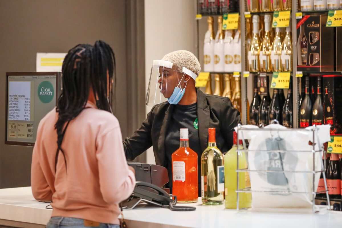 Сотрудник в маске на лице регистрирует покупку алкоголя в магазине Local Market Foods в Чикаго, штат Иллинойс, 8 апреля 2020 года. (Kamil Krzaczynski/AFP via Getty Images)