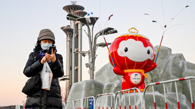 Женщина с телефоном перед инсталляцией талисмана зимних Паралимпийских игр 2022 года в Пекине, 13 января 2022 года. (JadeGao/AFP viaGettyImages)  | Epoch Times Россия