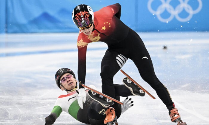 Hungary's Shaolin Sandor Liu (L) falls next to China's Ren Ziwei after crossing the finish line in the final A of the men's 1000m short track speed skating event during the Beijing 2022 Winter Olympic Games at the Capital Indoor Stadium in Beijing on February 7, 2022. (Photo by Anne-Christine POUJOULAT / AFP) (Photo by ANNE-CHRISTINE POUJOULAT/AFP via Getty Images) | Epoch Times Россия