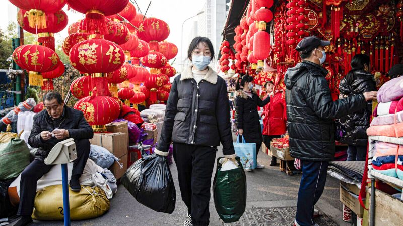 Люди в масках ходят мимо фонарей на улице 19 января 2022 года в Ухане, провинция Хубэй, Китай. Фото: Getty Images
 | Epoch Times Россия