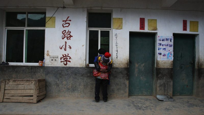 Пожилая женщина из народности И наблюдает за учащимися на уроке в школе в деревне Гулукан 17 ноября 2008 года в уезде Ханьюань, провинция Сычуань, Китай. Фото: Guang Niu/Getty Images
 | Epoch Times Россия