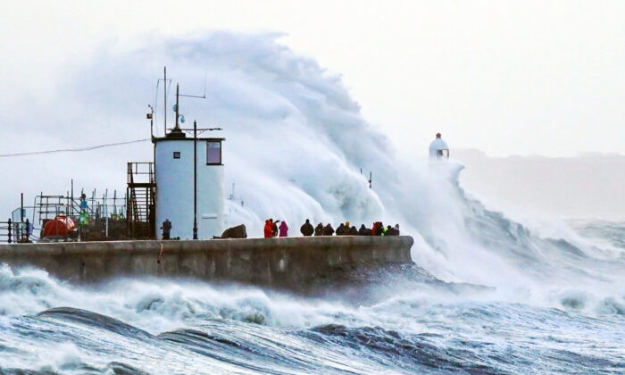 Волны разбиваются о морскую стену и маяк Порткол в Портколе, Бридженд, Уэльс, во время шторма «Юнис» на южном побережье Великобритании, 18 февраля 2022 года. (PA) | Epoch Times Россия