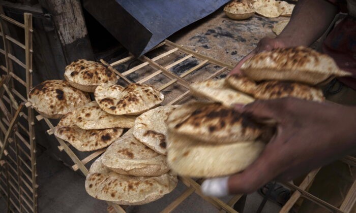 Рабочий собирает египетские традиционные лепёшки балади в пекарне в Эль-Шарабии, район Шубра, Каир, Египет, среда, 2 марта 2022 года. (NarimanEl-Mofty/AP Photo)
 | Epoch Times Россия