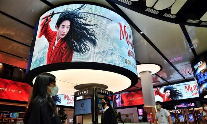 Люди проходят мимо рекламы фильма DisneysMulan в кинотеатре внутри торгового центра в Бангкоке, 8 сентября 2020 года. (LILLIAN SUWANRUMPHA/AFP viaGettyImages) | Epoch Times Россия