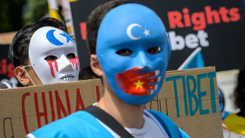 Тибетские и уйгурские активисты в масках во время акции протеста против зимних Олимпийских игр 2022 года в Пекине перед Олимпийским музеем в Лозанне 23 июня 2021 года, когда в акции приняли участие около 200 человек. Фото: PhotobyFabriceCOFFRINI / AFP
 | Epoch Times Россия