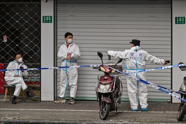 Полицейские и рабочие в защитной одежде рядом с некоторыми закрытыми зонами после обнаружения новых случаев заболевания COVID-19 в Шанхае 14 марта 2022 года. Фото: Hector Retamal/AFP via Getty Images