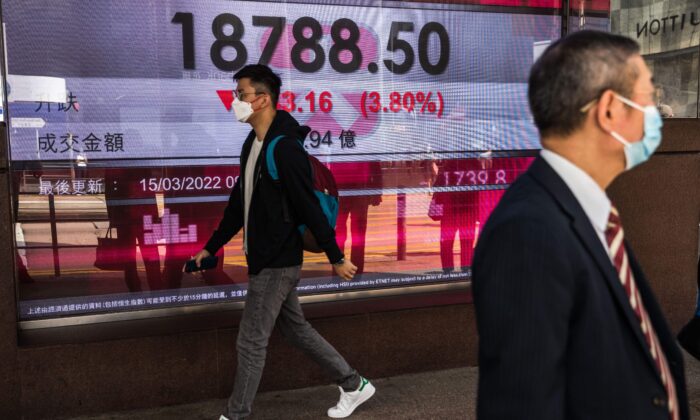 Мужчина проходит мимо дисплея с индексом Hang Seng в Гонконге, 15 марта 2022 года. Фото: (Dale de la Rey/AFP via Getty Images
 | Epoch Times Россия