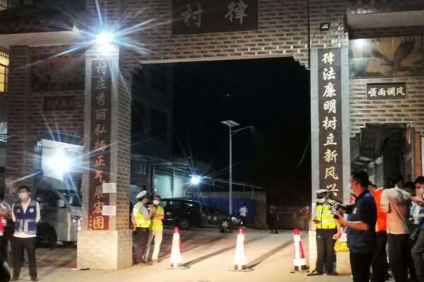 Полицейские стоят на страже у въезда в деревню, ведущую к месту авиакатастрофы в уезде Тэнсянь города Учжоу в южной китайской провинции Гуанси 21 марта 2022 года. (-/AFP через Getty Images)