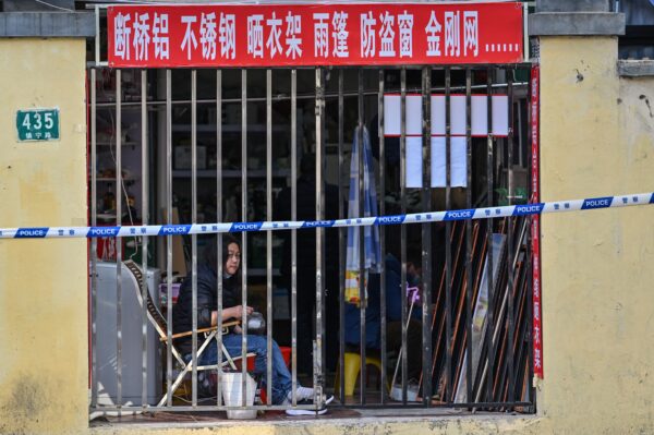 Человек смотрит на закрытый магазин рядом с закрытым районом в Шанхае, Китай, 23 марта 2022 года. Фото: Hector Retamal/AFP via Getty Images