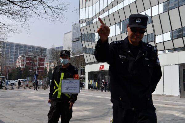 Полицейский пытается помешать съёмкам возле магазина шведского гиганта одежды H&M в Пекине, 25 марта 2021 года. (Greg Baker/AFP via Getty Images)