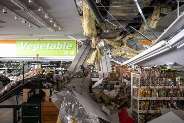 Мужчина убирает обломки повреждённого потолка в супермаркете в Сироиси, префектура Мияги, 17 марта 2022 года, после землетрясения магнитудой 7,4, которое накануне вечером потрясло восточную Японию. (Charly Triballeau/AFP via Getty Images)
