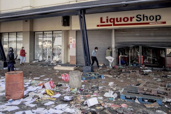 Офицер полиции ЮАР пытается разогнать участников беспорядков, грабящих магазин спиртных напитков в торговом центре Jabulani Mall в районе Соуэто в Йоханнесбурге 12 июля 2021 года. (Luca Sola/AFP via Getty Images)