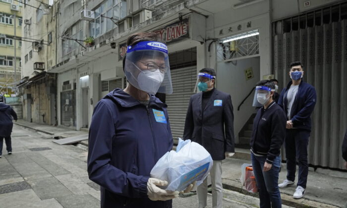 Глава администрации Гонконга Кэрри Лам (слева) держит пакет материалов по профилактике COVID-19, которые будут доставлены людям во время противоэпидемического мероприятия в Гонконге, 2 апреля 2022 года. Фото: Kin Cheung/AP Photo
 | Epoch Times Россия