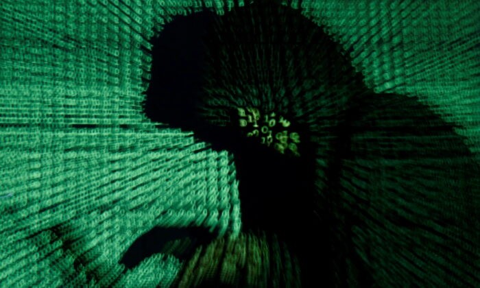 Мужчина держит ноутбук, когда на него проецируется киберкод. Фото: Kacper Pempel/Reuters
 | Epoch Times Россия