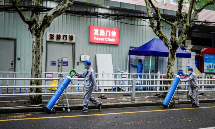 Рабочие доставляют кислородные баллоны возле больницы во время блокировки в Шанхае, Китай, 14 апреля 2022 года. (Aly Song/Reuters) | Epoch Times Россия