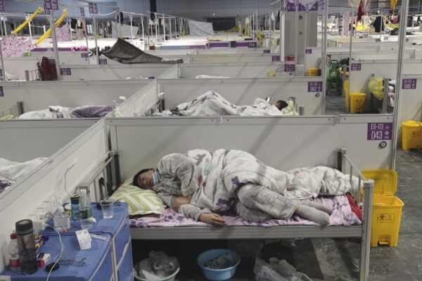 Жители отдыхают во временной больнице, переоборудованной из Национального выставочного и конференц-центра для заражённых COVID-19, в Шанхае, Китай, 18 апреля 2022 года. (Chinatopix via AP)