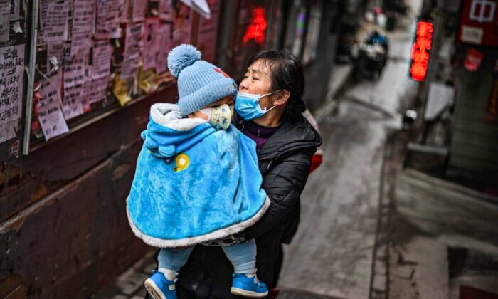 Женщина в маске с ребёнком на руках в Ухане, провинция Хубэй в центральной части Китая, 22 января 2021 года. (Hector Retamal/AFP via Getty Images)
 | Epoch Times Россия
