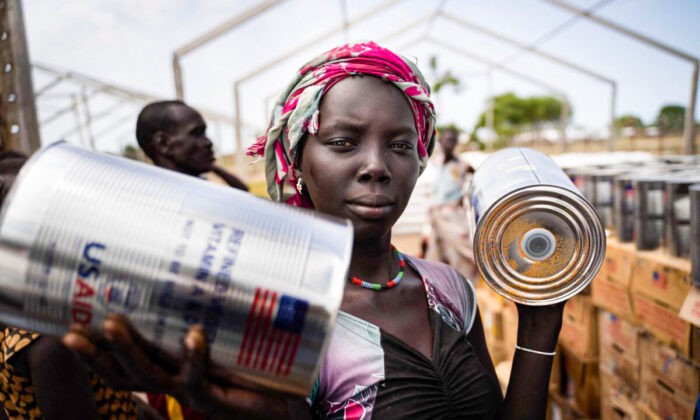 Женщина получает банки с маслом во время раздачи продуктов Всемирной продовольственной программой ООН в Гумуруке, Южный Судан, 10 июня 2021 года. Фото: SimonWohlfahrt/AFPviaGettyImages | Epoch Times Россия