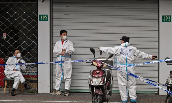 Полиция и рабочие в защитном снаряжении рядом с закрытыми зонами после выявления новых случаев заболевания COVID-19 в Шанхае, 14 марта 2022 года.(Hector Retamal/AFP via Getty Images) | Epoch Times Россия