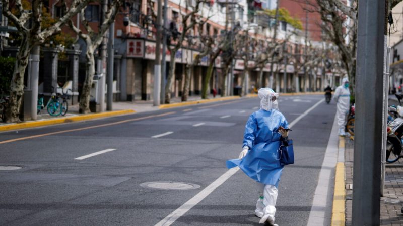 Рабочий в защитном костюме наблюдает за улицей во время начала второго этапа двухэтапной операции по блокированию распространения вируса COVID-19 в Шанхае, Китай, 1 апреля 2022 года. (AlySong/Reuters)  | Epoch Times Россия