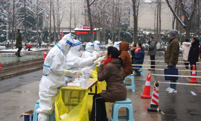 Медицинские работники в защитных костюмах берут мазки у жителей во время общегородского тестирования на нуклеиновые кислоты после случаев заболевания COVID-19 в Чжэнчжоу, провинция Хэнань, Китай, 5 января 2022 года. (CNS photo via Reuters) | Epoch Times Россия