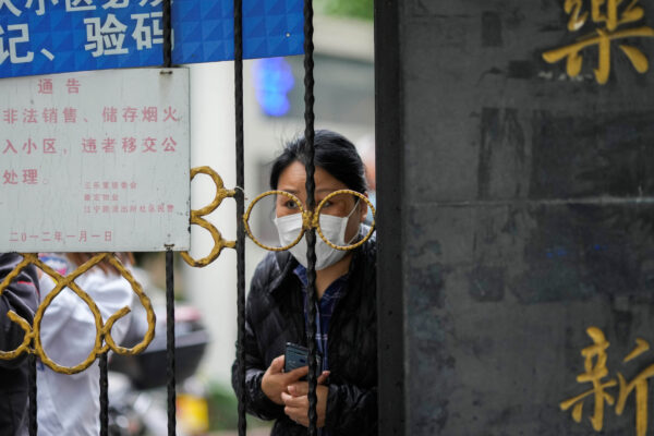 Житель выглядывает из ворот, закрывающих вход в жилой район, заблокированный в Шанхае, Китай, 13 апреля 2022 года. (Aly Song/Reuters)