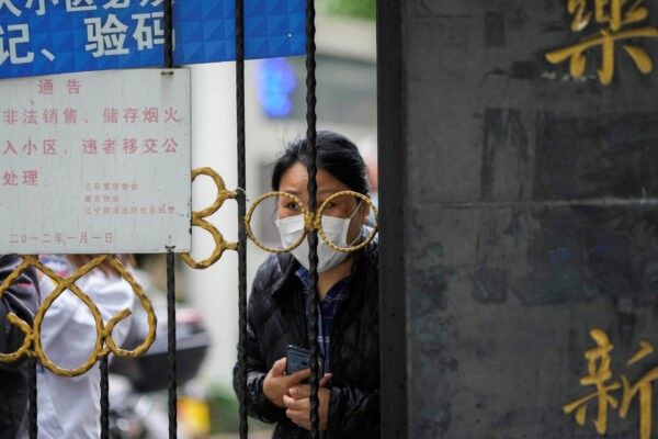 Житель выглядывает из-за ворот, закрывающих вход в жилой район, находящийся под изоляцией в Шанхае, 13 апреля 2022 года. (Aly Song/Reuters)