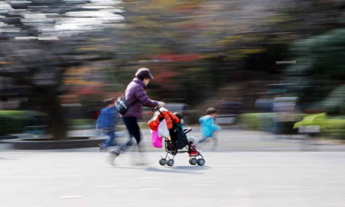Файловое изображение женщины с коляской, гуляющей с детьми в парке в Токио. (Yoshikazu Tsuno/AFP via Getty Images) | Epoch Times Россия