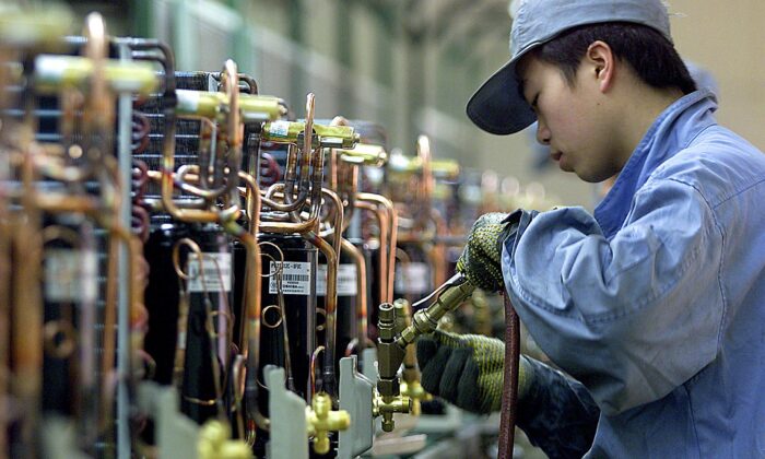 Китайский рабочий чинит компрессоры на линии по производству кондиционеров в японской компании по производству бытовых электроприборов Хитачи в Шанхае, 13 марта 2003. (Liu Jin/AFP via Getty Images) | Epoch Times Россия