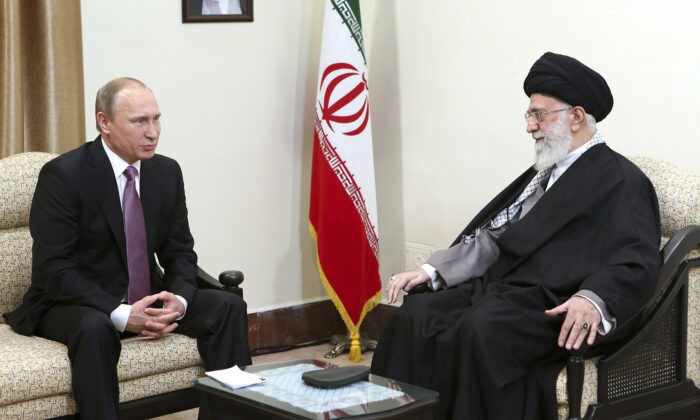 Верховный лидер аятолла Али Хаменеи (справа) и президент России Владимир Путин на встрече в Тегеране, Иран. На стене висит портрет покойного основателя иранской революции Аятоллы Хомейни. (OfficeoftheIranianSupremeLeadervia AP) | Epoch Times Россия