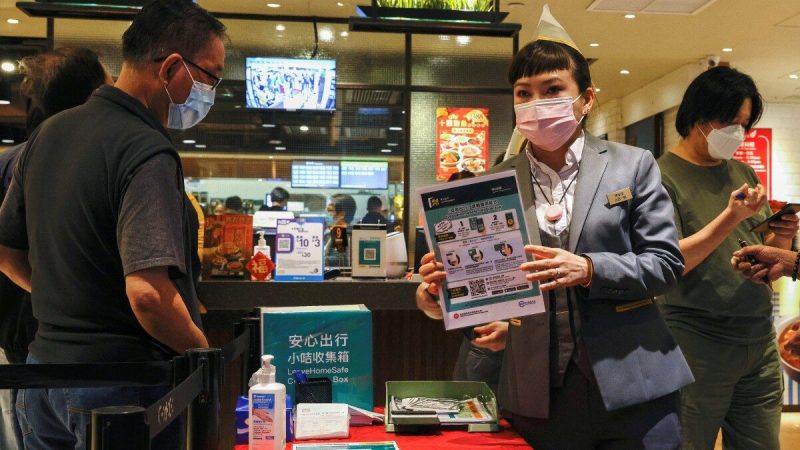Сотрудник знакомит посетителей с приложением для отслеживания контактов LeaveHomeSafe COVID-19 в ресторане после вспышки COVID-19 в Гонконге, 18 февраля 2021 г. Фото: Tyrone Siu/Reuters    | Epoch Times Россия