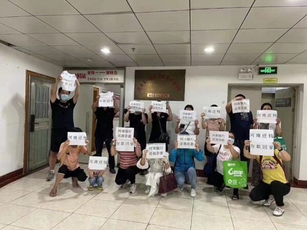 Клиенты четырёх банков провинции Хэнань держат бумаги с надписью «Банки Хэнани возвращают мои вклады» в Чжэнчжоу, провинция Хэнань, Китай. (Предоставлено изданию The Epoch Times)