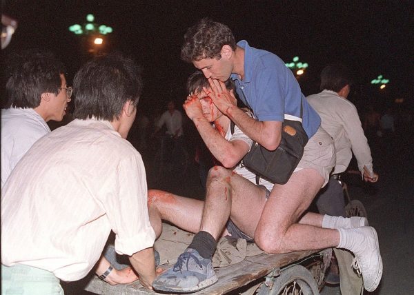 Неизвестного иностранного журналиста (второй справа) выносят с места столкновения между армией и студентами на площади Тяньаньмэнь 4 июня 1989 года. По данным Amnesty International, через пять лет после подавления китайского продемократического движения тысячи его участников остаются в тюрьмах. (Tommy Cheng/AFP/Getty Images)