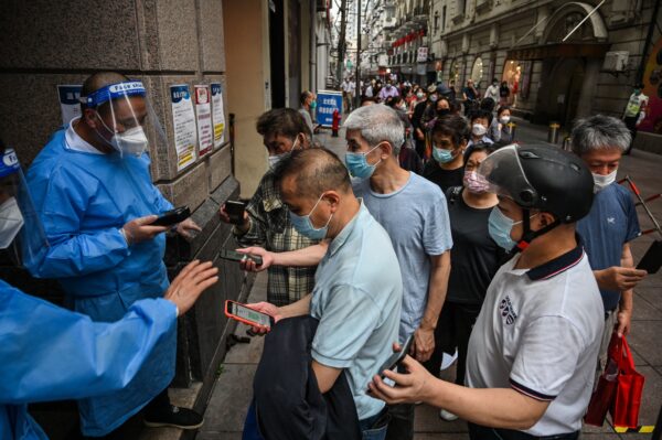 Сотрудники сканируют QR-коды здоровья людей, входящих в торговый центр в районе Хуанпу в Шанхае 1 июня 2022 года. Фото: Hector Retamal/AFP via Getty Images