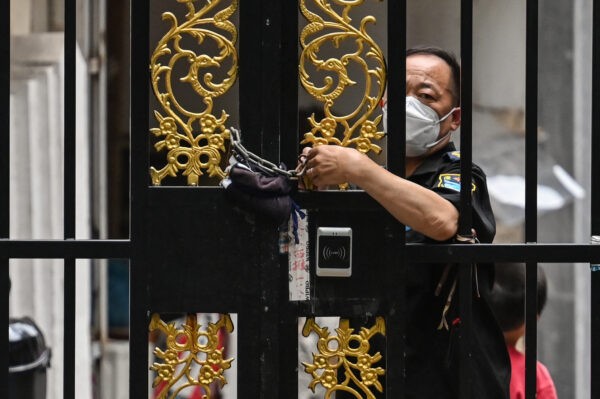 Сотрудник службы безопасности запирает дверь в районе, где действует режим изоляции COVID-19, в районе Цзинъань в Шанхае 2 июня 2022 года. Фото: Hector Retamal/AFP via Getty Image