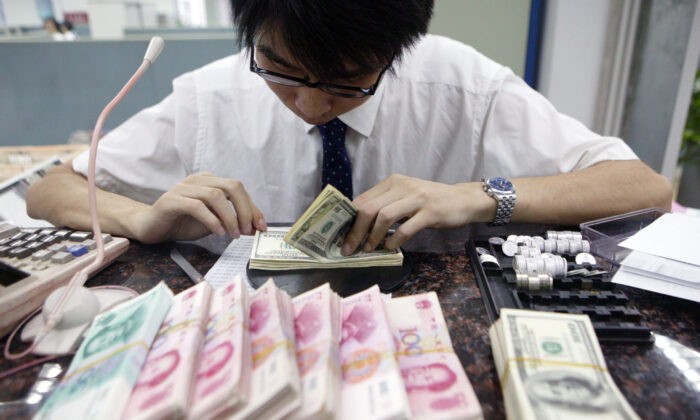 Клерк пересчитывает пачки китайских юаней и американских долларов в банке в Шанхае, Китай, 22 июля 2005. (ChinaPhotos/GettyImages) | Epoch Times Россия