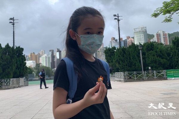 Руру, 10-летняя девочка, показала репортёру пластиковый блок в форме свечи в своей руке. Она пришла сегодня в Козуэй Бэй с родителями к парку Виктория. (Tang Jianfeng/The Epoch Times)