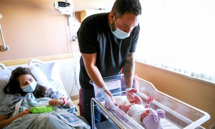  
Отец меняет подгузник своей новорождённой в больнице в Эппл-Вэлли, Калифорния, 30 марта 2021 года. Фото: Mario Tama/Getty Images | Epoch Times Россия