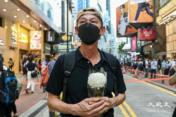 В 33-ю годовщину резни на площади Тяньаньмэнь 4 июня Лю в Гонконге отмечал это событие в Козуэй-Бэй в чёрном топе и с белым цветком в руках, 4 июня 2022 г. Фото: Song Beelong/The Epoch Times | Epoch Times Россия